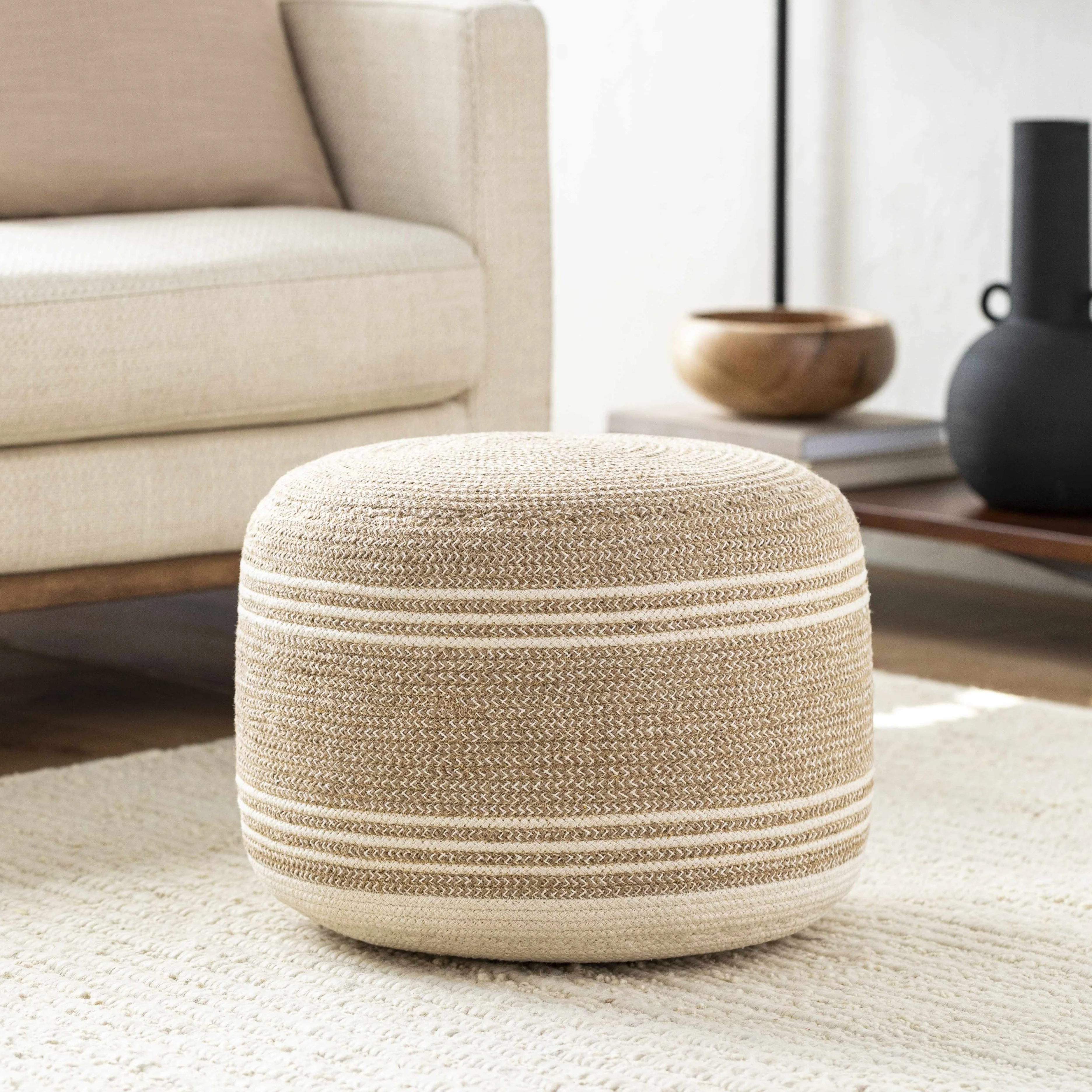 Natural woven fabric pouf footrest with cream stripes for living room seating and decor.